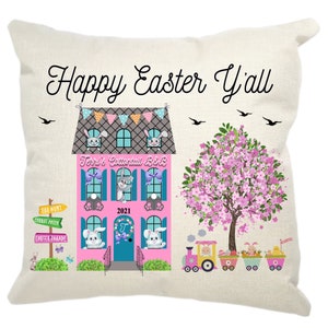 May include: A pink and gray house with a blue door and windows. The house has a sign that says "Terri's Cottontail B&B" and the year 2021. There are bunnies in the windows and a train with bunnies in the cars. The text "Happy Easter Y'all" is at the top of the image.