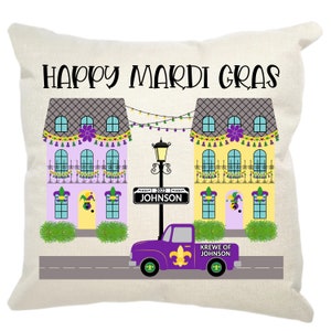 May include: A decorative pillow with a Mardi Gras theme. It features two colorful houses with purple, yellow, and green accents, a street lamp, and a purple truck with the text "Krewe of Johnson". The text "Happy Mardi Gras" is at the top of the pillow.