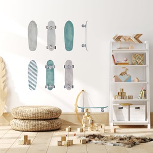 May include: A white wall with a collection of teal and gray skateboard decals. The decals are arranged in a grid pattern. There is a white bookshelf with a wooden arrow on the top shelf. The bookshelf is filled with books, toys, and decorative items.