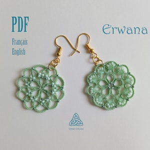 Może przedstawiać: Para zielonych koralikowych kolczyków z złotymi haczykami. Kolczyki mają kształt kwiatu z centralnym koralikiem. Kolczyki są oznaczone "Erwana".