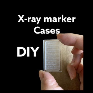 May include: A clear, rectangular X-ray marker case is held between fingers against a brown background. The case has a frosted appearance with horizontal lines. The words "X-ray marker Cases" and "DIY" are in white text.