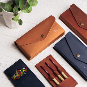May include: Four leather cases for darts, each with a different personalized name: "Max", "Tax", "Mr", and a case with darts. The cases are brown and blue, with a flap closure.