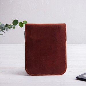 Puede incluir: Una funda de cuero marr&oacute;n para un lector electr&oacute;nico, sobre un fondo blanco.