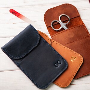 May include: Three personalized leather pouches with different initials, one with a pair of small scissors inside. The pouches are brown, blue, and tan.