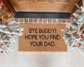 May include: A brown coir doormat with the text "Bye Buddy! Hope you find your Dad." in black lettering.
