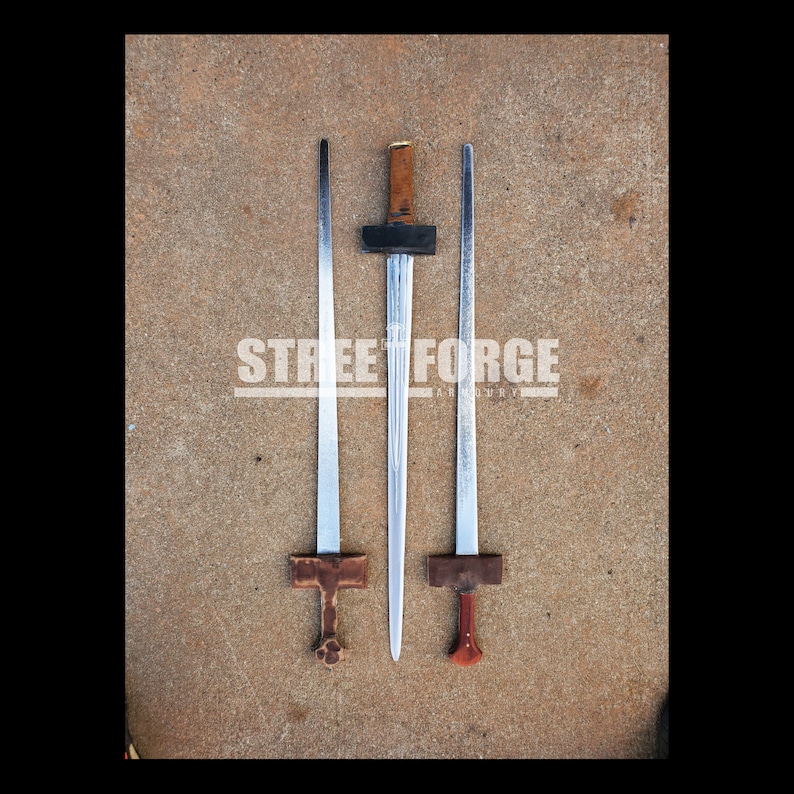 Puede incluir: Tres espadas con hojas plateadas y mangos de madera. Las espadas est&aacute;n dispuestas sobre una superficie de hormig&oacute;n. El texto "STREET FORGE" es visible en la imagen.