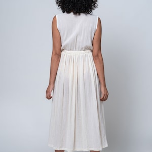 K&ouml;nnte beinhalten: Ein wei&szlig;es, &auml;rmelloses Kleid mit geraffter Taille und einem flie&szlig;enden Rock. Das Kleid ist aus einem leichten Stoff gefertigt und hat eine lockere Passform.