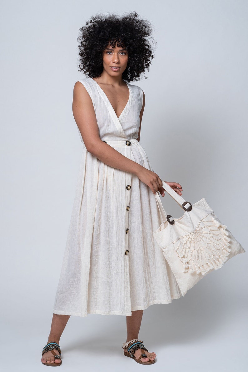 K&ouml;nnte beinhalten: Ein wei&szlig;es, &auml;rmelloses Midi-Kleid mit Knopfleiste und einer ger&uuml;schten Tragetasche.