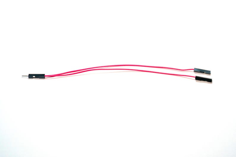 May include: Two pink electrical jumper wires with black plastic connectors at each end. One end features a single male pin connector, while the other end splits into two separate female socket connectors for electronic circuit connections.