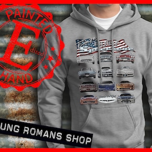 May include: Gray hooded sweatshirt with a graphic of a vintage American flag and a collection of Chevrolet Corvette cars. The text "Evolution of the American Sportscar" is printed above the cars. The text "Painted by Hand" is in a red circle stamp on the left side of the image. The text "Young Romans Shop" is printed below the image.