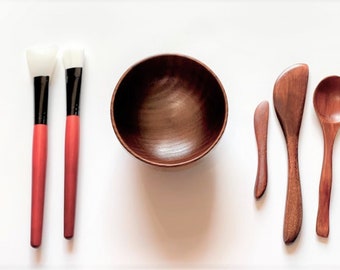 May include: A set of wooden tools for applying face masks, including two silicone brushes, a small wooden bowl, a small wooden spatula, a larger wooden spatula, and a wooden spoon.