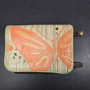 Cartera Fossil, en excelentes condiciones, detalle de mariposa naranja, 3 secciones con cierre, ranura para billetes, monedero, ranuras para identificación, cuero genuino.