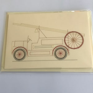 May include: A cream-coloured card with a black and red thread embroidery of a fire engine. The engine has a ladder, a large wheel at the back, and two smaller wheels at the front.