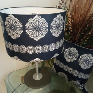 May include: A blue and white patterned lamp with a silver base and a matching cushion. The lamp is on a glass table.