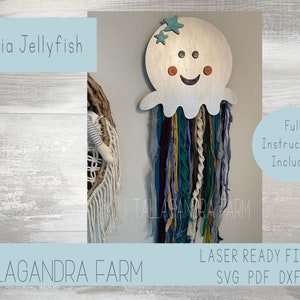 May include: A silver metal jellyfish with a smiling face and two stars on top. The jellyfish has long strands of raffia hanging from the bottom. The text "Raffia Jellyfish" is in the top left corner of the image. The text "Full Instructions Included" is in the top right corner of the image. The text "TALLAGANDRA FARM" is in the bottom left corner of the image. The text "LASER READY FILES SVG PDF DXF" is in the bottom right corner of the image.