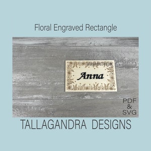 May include: A wooden rectangle with a floral design engraved around the edges. The name "Anna" is engraved in the centre. The rectangle is on a woodgrain background. The text "PDF & SVG" is in the bottom right corner. The text "TALLAGANDRA DESIGNS" is at the bottom of the image.