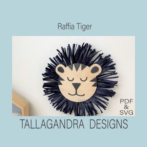May include: A wooden tiger head with black stripes and closed eyes, surrounded by a blue raffia mane. The text "Raffia Tiger" is above the image and "TALLAGANDRA DESIGNS" is below the image. The text "PDF & SVG" is in the lower right corner of the image.