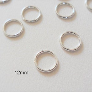 May include: Silver jump rings, 12mm in diameter, with a textured finish. These rings are great for jewellery making, crafts, and other projects.