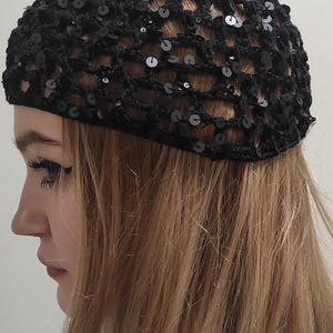 May include: A black crochet hat with sequins. The hat is made of a fine mesh material and has a loose fit.