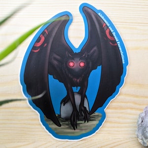 May include: A blue sticker with a black creature with red eyes and wings. The creature is standing on a rock. The text "Alchemist and Druid Formulations" is on the sticker.