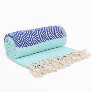 May include: A turquoise and navy blue beach towel with a chevron pattern and white fringe.