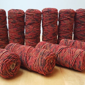 Può includere: Dieci bobine di cordoncino elastico con motivo rosso e nero. Il cordoncino è avvolto strettamente attorno a ogni bobina.