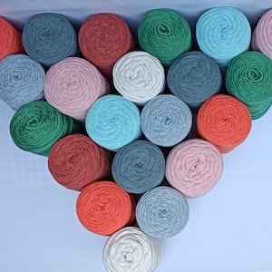Pode incluir: Uma coleção de 18 novelos de lã coloridos dispostos em forma de triângulo. Os novelos de lã são em tons de vermelho, verde, azul, rosa e cinza.
