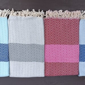 May include: Four woven cotton throws with fringe edges. The throws are in different colors and patterns: light blue with navy blue stripes, gray with gray stripes, burgundy with pink stripes, and navy blue with navy blue stripes.