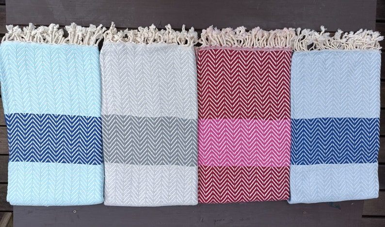 May include: Four woven cotton throws with fringe edges. The throws are in different colors and patterns: light blue with navy blue stripes, gray with gray stripes, burgundy with pink stripes, and navy blue with navy blue stripes.