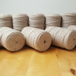 May include: A collection of 12 spools of natural beige twine, each wound tightly and ready for crafting projects.