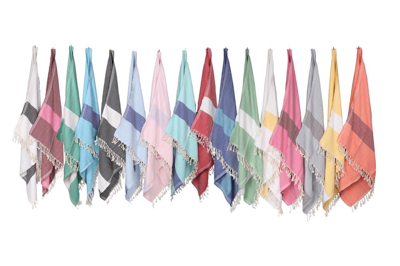 May include: A collection of 14 colorful striped towels with fringe edges hanging on a white background. The towels are in various colors, including red, blue, green, yellow, pink, and gray.