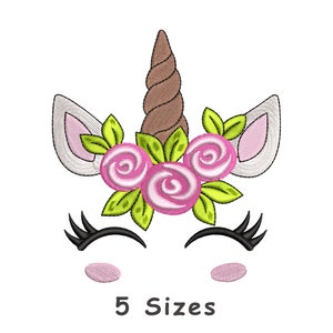 Puede incluir: Cara de unicornio bordada con los ojos cerrados, cuerno marrón, flores rosas y hojas verdes. El texto "5 Sizes" está debajo de la imagen.
