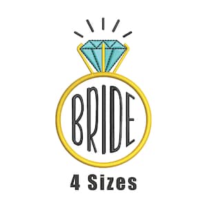 May include: A gold ring with a blue diamond and the word "BRIDE" in black lettering. The ring is surrounded by a white background.