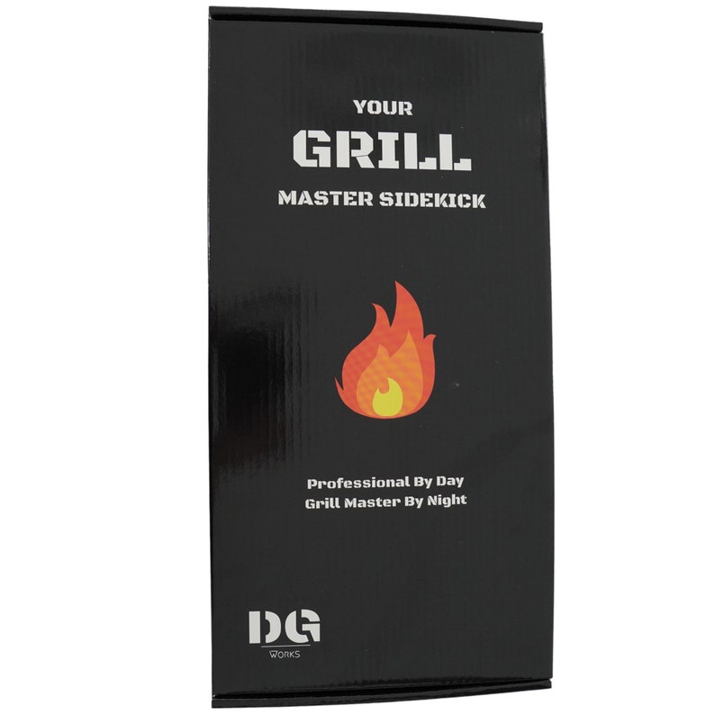 Op de afbeelding: Zwarte doos met witte tekst die "Your Grill Master Sidekick" luidt en een rode en gele vlamgrafiek. De tekst "Professional By Day Grill Master By Night" staat ook op de doos. De onderkant van de doos heeft een wit logo met de tekst "DG Works".