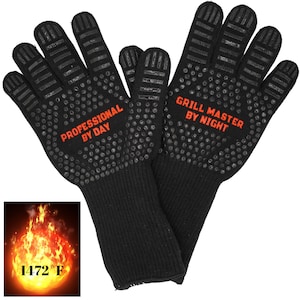 Op de afbeelding: Een paar hittebestendige zwarte handschoenen met een textuur grip. De handschoenen hebben de tekst "Professional by Day" op de ene handschoen en "Grill Master by Night" op de andere. De handschoenen zijn bestand tegen 1472 graden Fahrenheit.