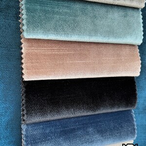 May include: A close-up of seven fabric swatches in different colors and textures. The swatches are arranged in a stack, with the top swatch being a light brown color and the bottom swatch being a white color. The swatches are all velvet.