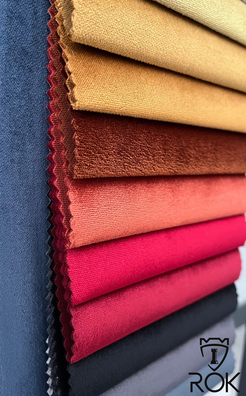 May include: A stack of fabric swatches in various colours, including navy blue, brown, red, and orange. The fabric has a soft, velvety texture.