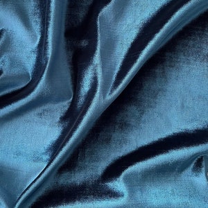 May include: Close-up of a teal blue fabric with a subtle sheen. The fabric is draped and folded, showcasing its texture and drape.