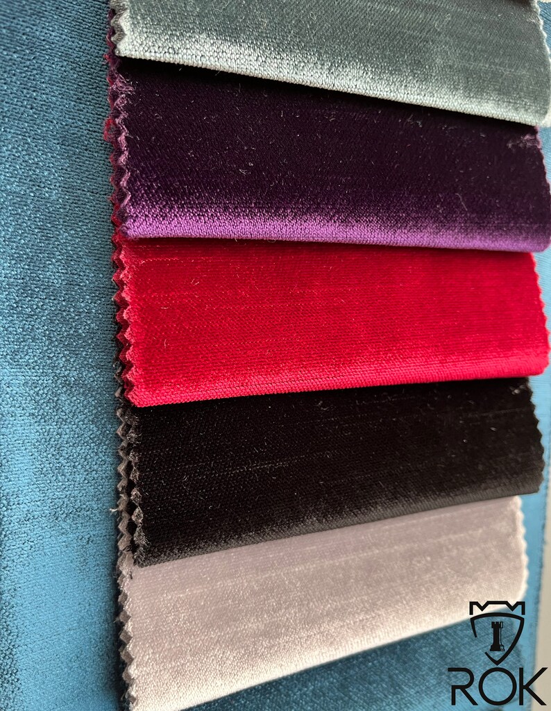 May include: A stack of five fabric swatches in different colors. The swatches are arranged from top to bottom: teal, purple, red, black, and gray. The bottom swatch has the text "ROK" in white letters.
