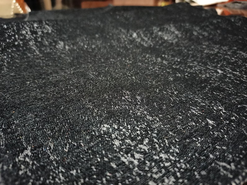May include: Close-up of a black fabric with a subtle shimmery texture. The fabric has a slightly rough, textured surface.