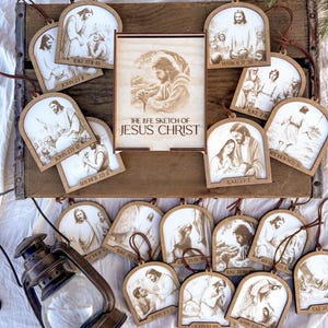 May include: Wooden Christmas ornaments featuring illustrations of Jesus Christ and biblical scenes. Each ornament has a brown leather loop for hanging. A wooden frame with the text "THE LIFE SKETCH OF JESUS CHRIST" is also present.