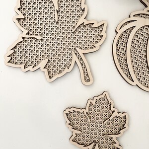 May include: Three wooden craft projects in the shape of a maple leaf and a pumpkin. The leaves and pumpkin are made of a woven wood material.