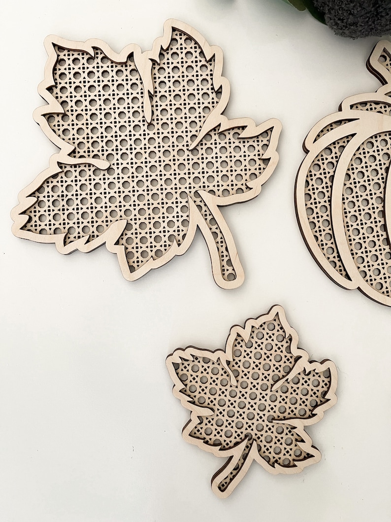 May include: Three wooden craft projects in the shape of a maple leaf and a pumpkin. The leaves and pumpkin are made of a woven wood material.