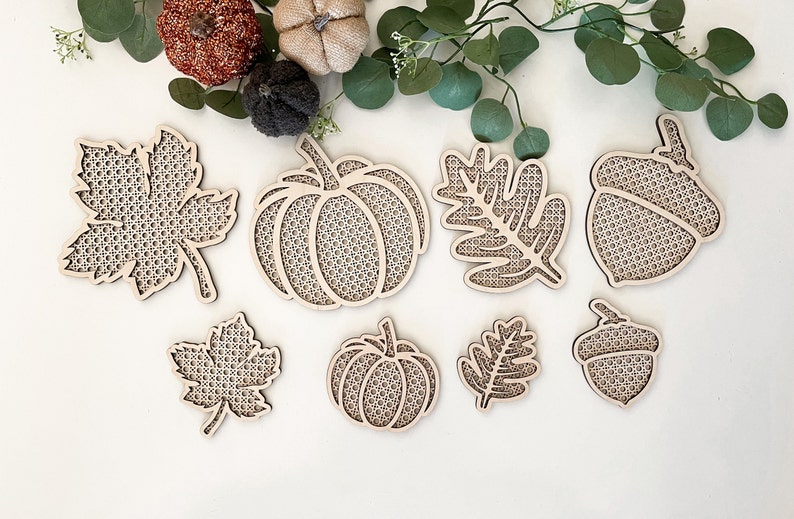 May include: Eight wooden craft shapes featuring autumn themes. The shapes include a pumpkin, acorn, and leaves. The shapes are unfinished and ready to be painted or decorated.