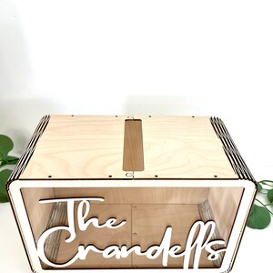 May include: A wooden box with a slot on the top for cards. The box is clear on the front and has the text "The Crandells" written in white.
