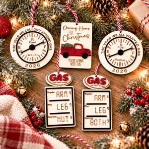May include: Five wooden Christmas ornaments featuring fuel gauge designs with text reading The Year We Couldn't Afford Gas 2026, Driving Home For Christmas, The Year We All Wanted Gas 2026, and gas price signs reading Arm, Leg, Nut, and Both.