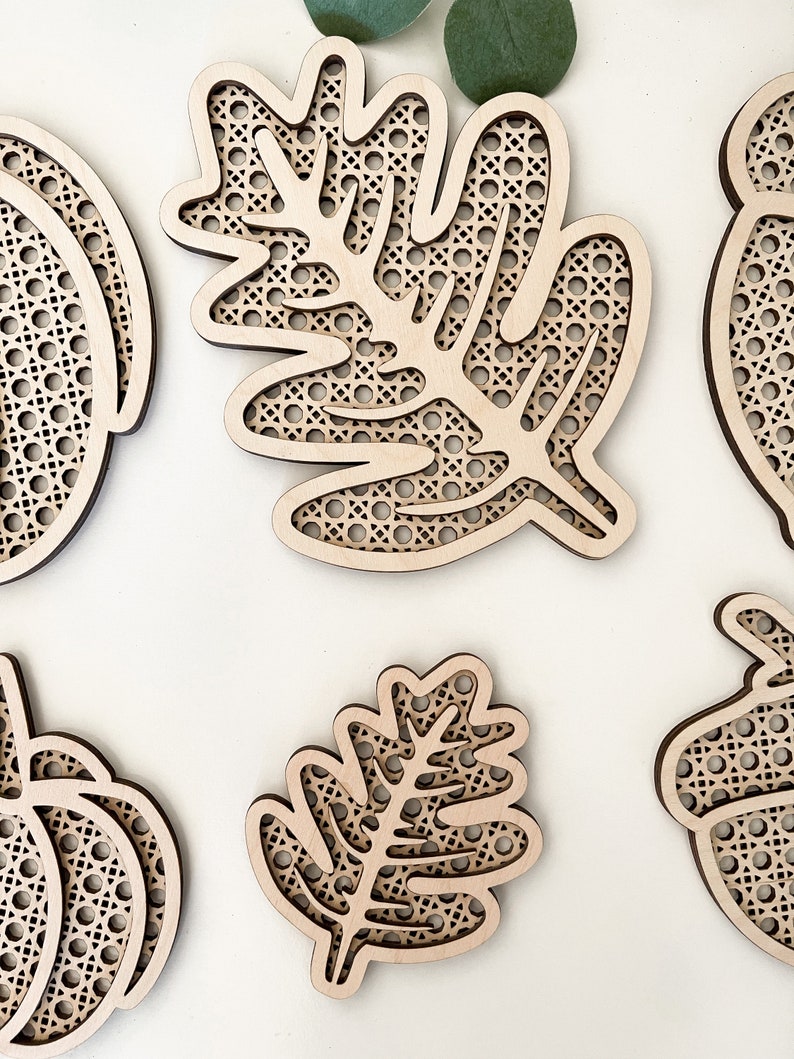 May include: Five wooden cutouts of leaves and pumpkins with a woven pattern. The cutouts are unfinished and ready to be painted or stained.