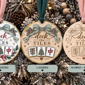 May include: Three circular ornaments with pink or green ribbons. Each features the text "deck the TILES" and three mahjong tiles depicting mistletoe, a Christmas tree, and a red character. One is UV printed, one is layered, and one is engraved.