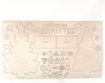 Puede incluir: Un kit de manualidades de madera para decorar un árbol de Navidad. El kit incluye dos contornos de árboles, una variedad de adornos y el texto "Decora tu propio árbol de Navidad".