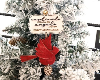 May include: Wooden Christmas ornament featuring a red cardinal with a sign that reads "Cardinals appear when angels are near. Brandt William Norton".